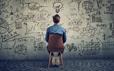 Back view of freelancer man sitting in front of wall with strategy and creating a plan.