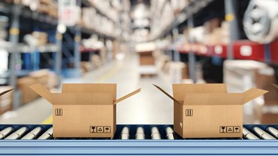 Cardboard boxes on conveyor roller with racks on background