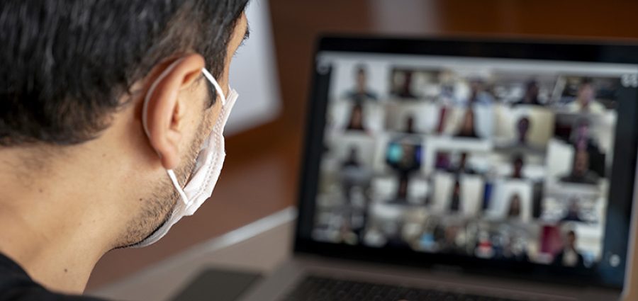 Man using a mask and having a video conference with work team am